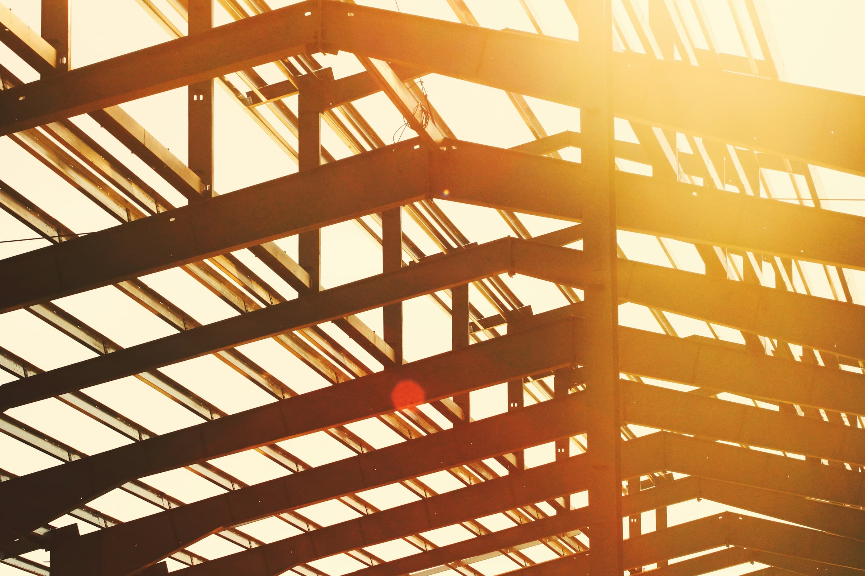 The steel frame of a pre-engineered building, silhouetted against a low sun