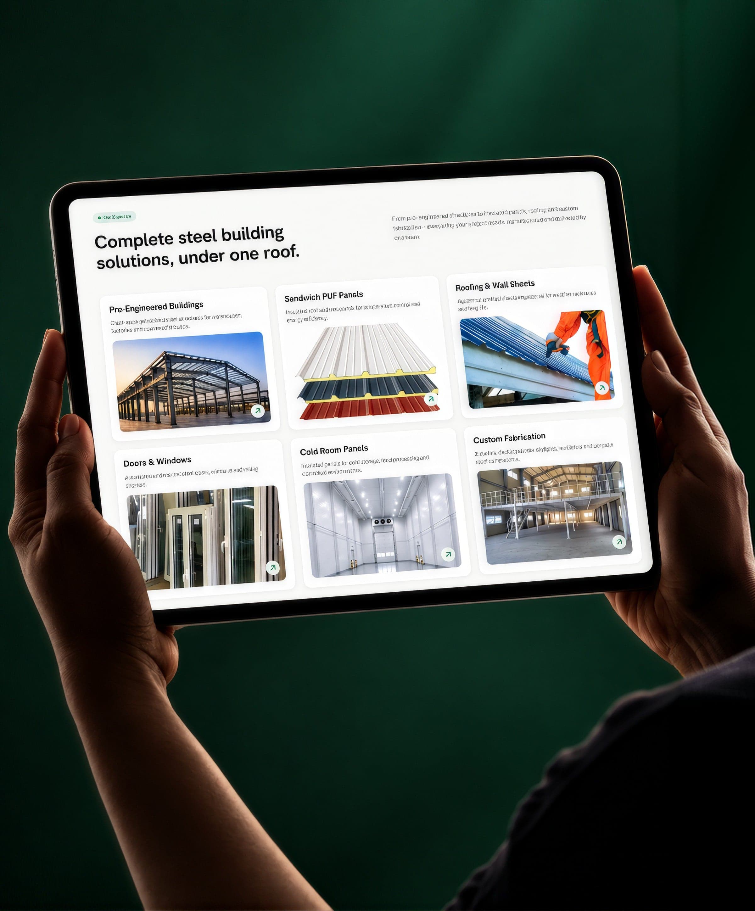 Hands holding a tablet open on the PrimeNMS services page: “Complete steel building solutions, under one roof.” above six product cards