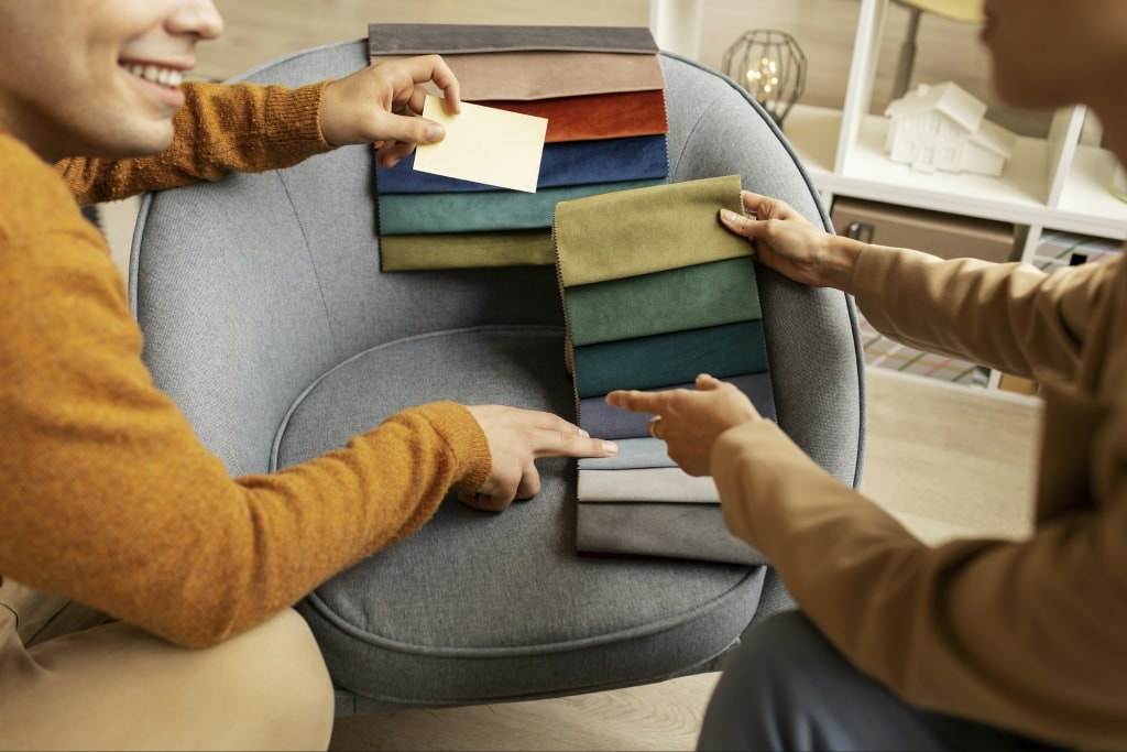Two people comparing fabric swatches on an armchair in a showroom