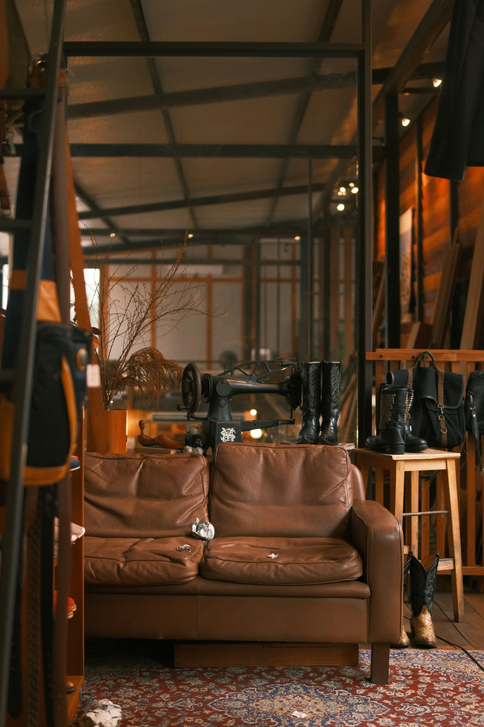 A workshop with a vintage sewing machine, leather boots and bags in warm light