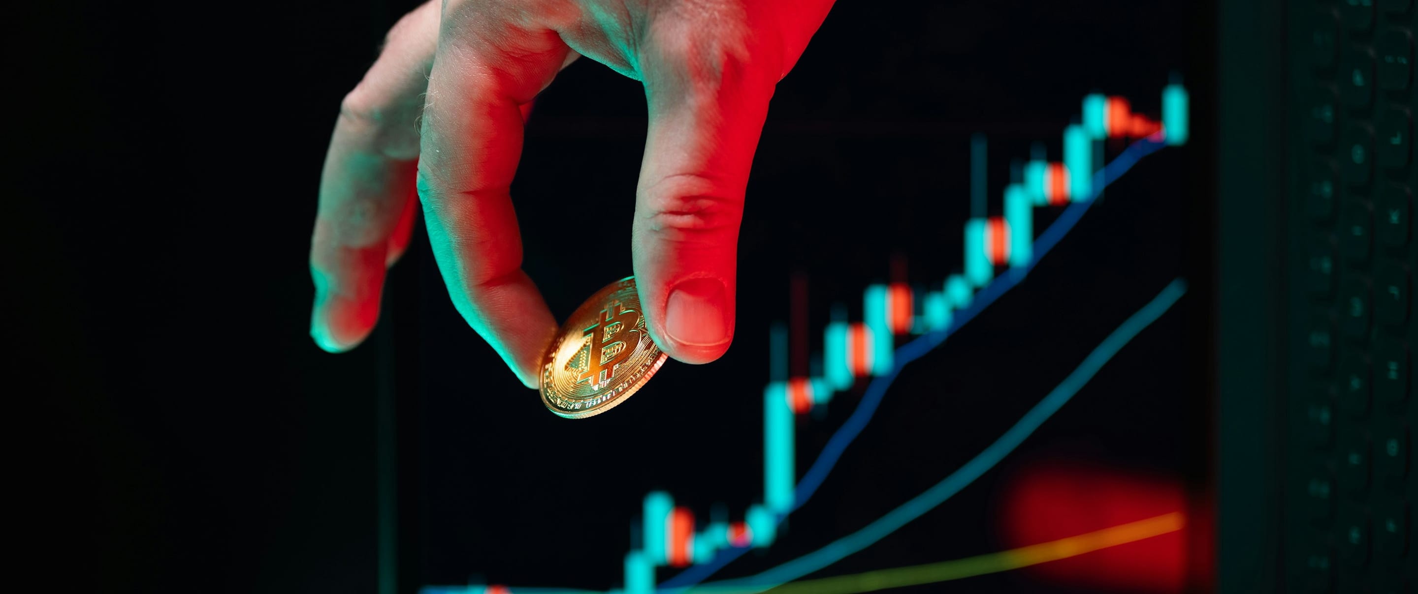 A hand holding a gold coin in front of a rising price chart
