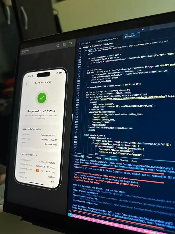 A phone showing a Payment Successful screen, in front of a monitor full of code